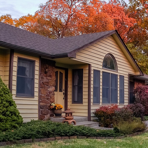 View of traditional Midwestern house in fall; colorful trees and bushes in front and behind the house